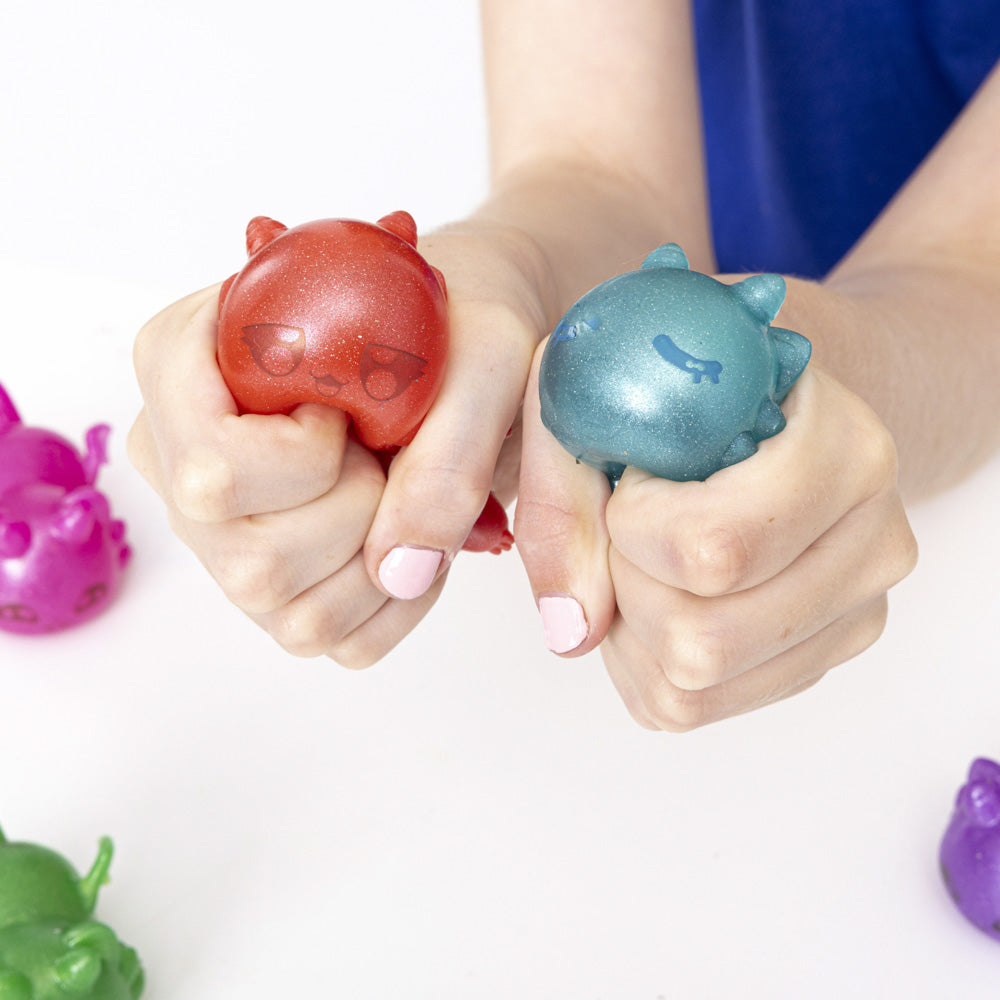 Hands squeezing the Aphmau Mystery MeeMeows Squishy Dragons fidget toys