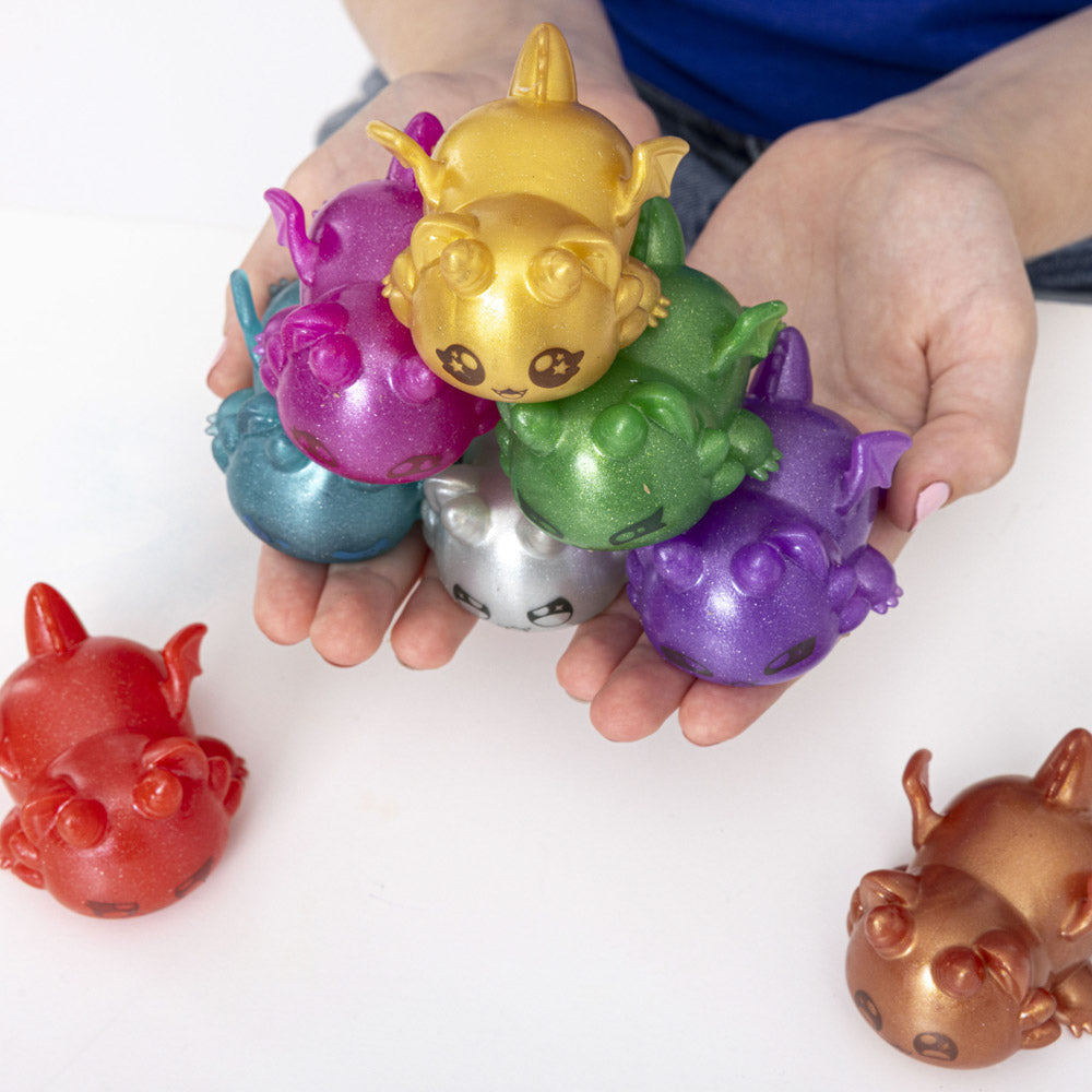 Hands holding the Aphmau Mystery MeeMeows Squishy Dragons fidget toys