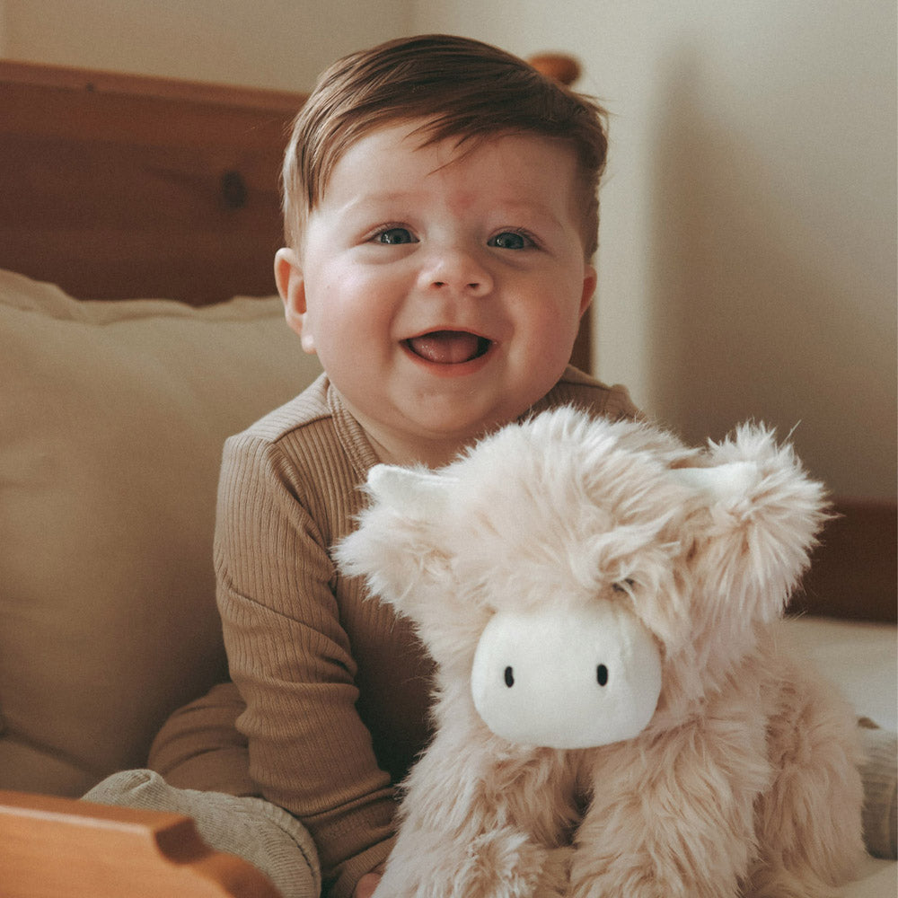 Baby holding the Snuggle Bunnies Hilda the Highland Cow soft toy