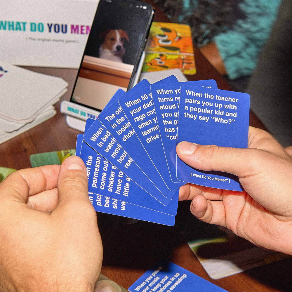 Hands holding the What Do You Meme? GIF Edition card game